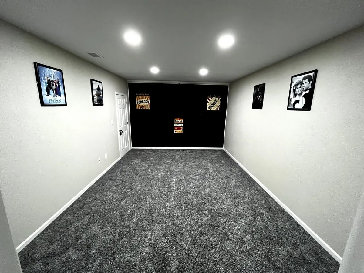 A home theater room adorned with nostalgic movie posters and a popcorn sign creates a playful, cinematic atmosphere. The space is ready for group movie nights or lively game tournaments, promising memorable evenings without ever leaving the comfort of home.