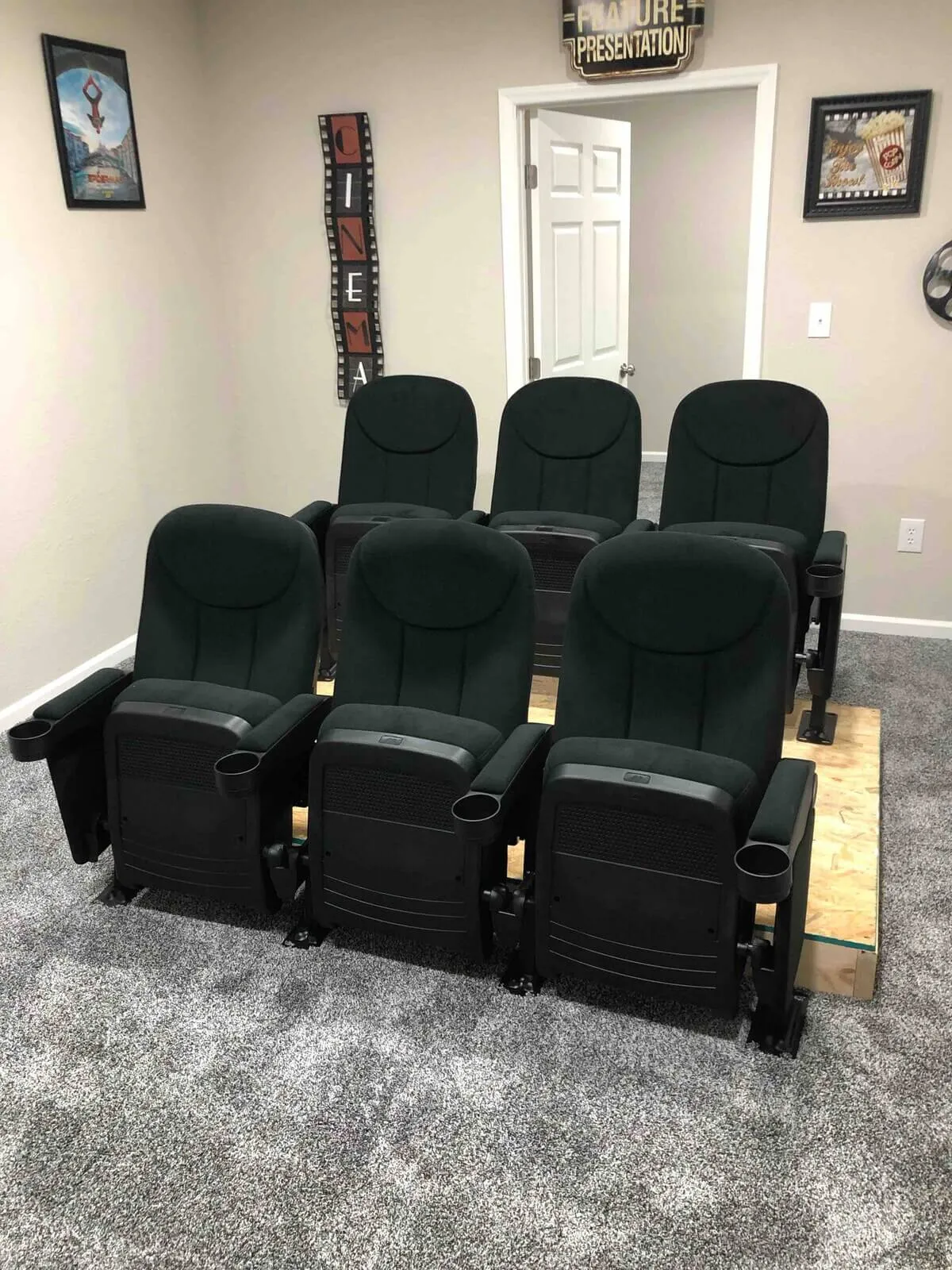 A cozy interior theater room with plush seating, cinema signs, and soft carpet flooring, creates an inviting space for immersive movie nights and family gatherings.