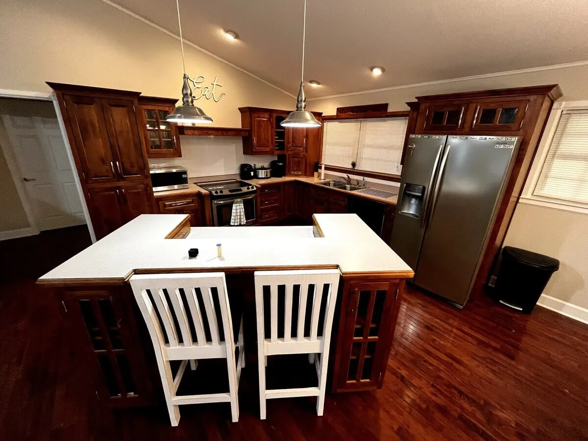 A welcoming kitchen with a central island, stainless steel appliances, and rich wood cabinetry, perfect for preparing meals and entertaining guests.