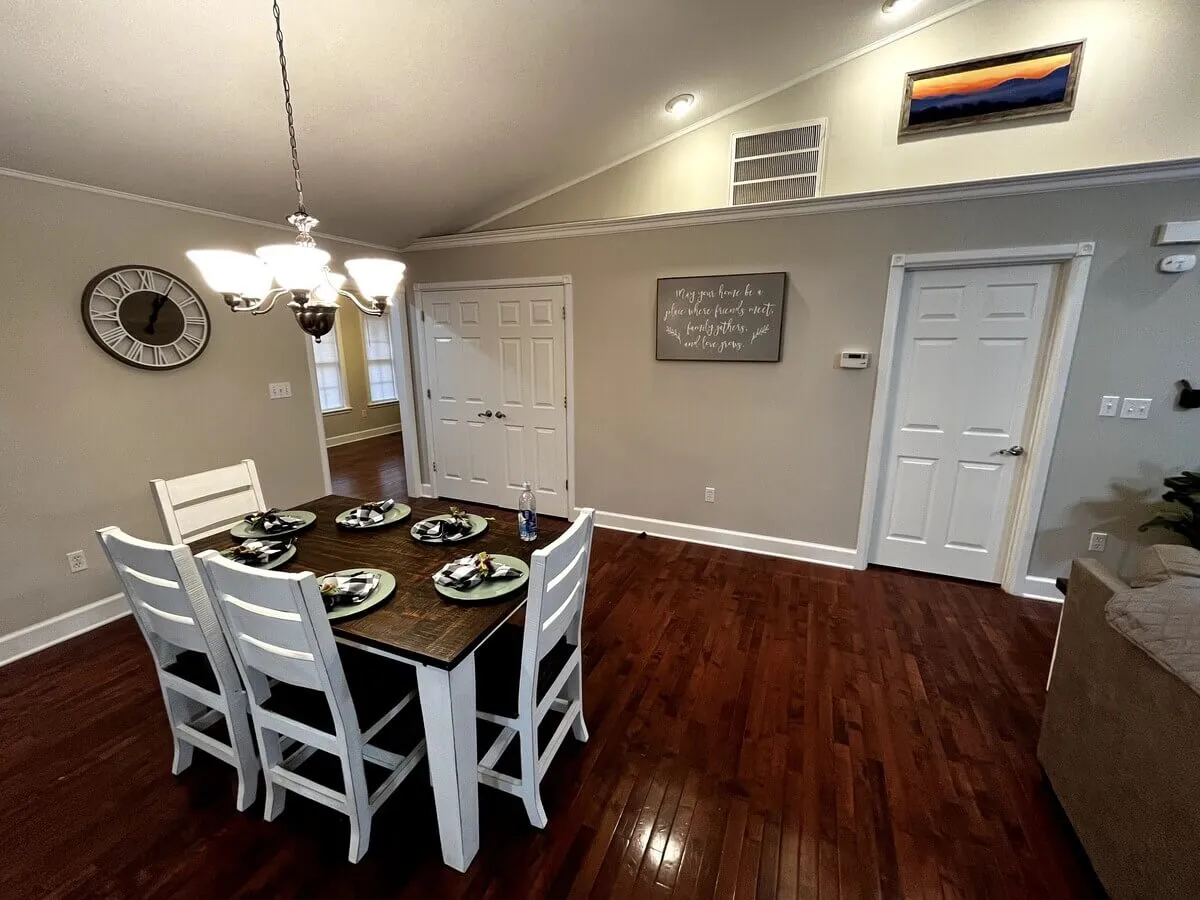 This interior shot features a spacious dining table under a striking chandelier, surrounded by warm wall art and décor. The inviting space is set for memorable group meals, celebrations, or game nights, capturing the spirit of togetherness.